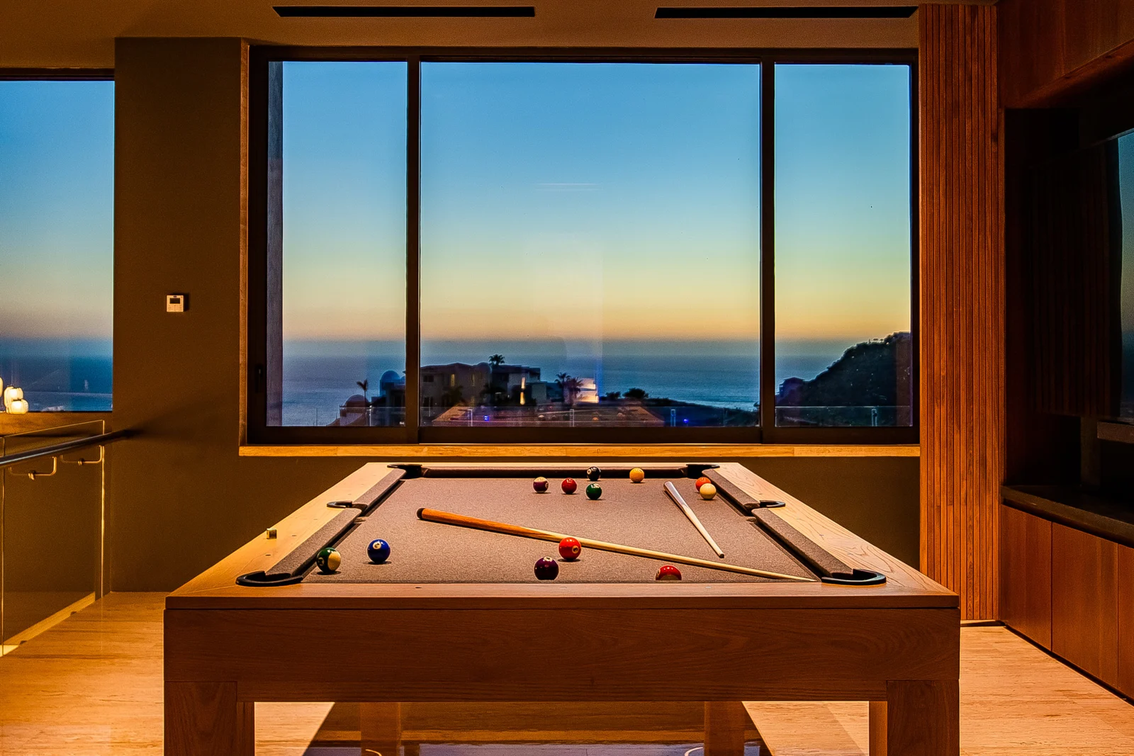 Pool table beside sunset-facing windows