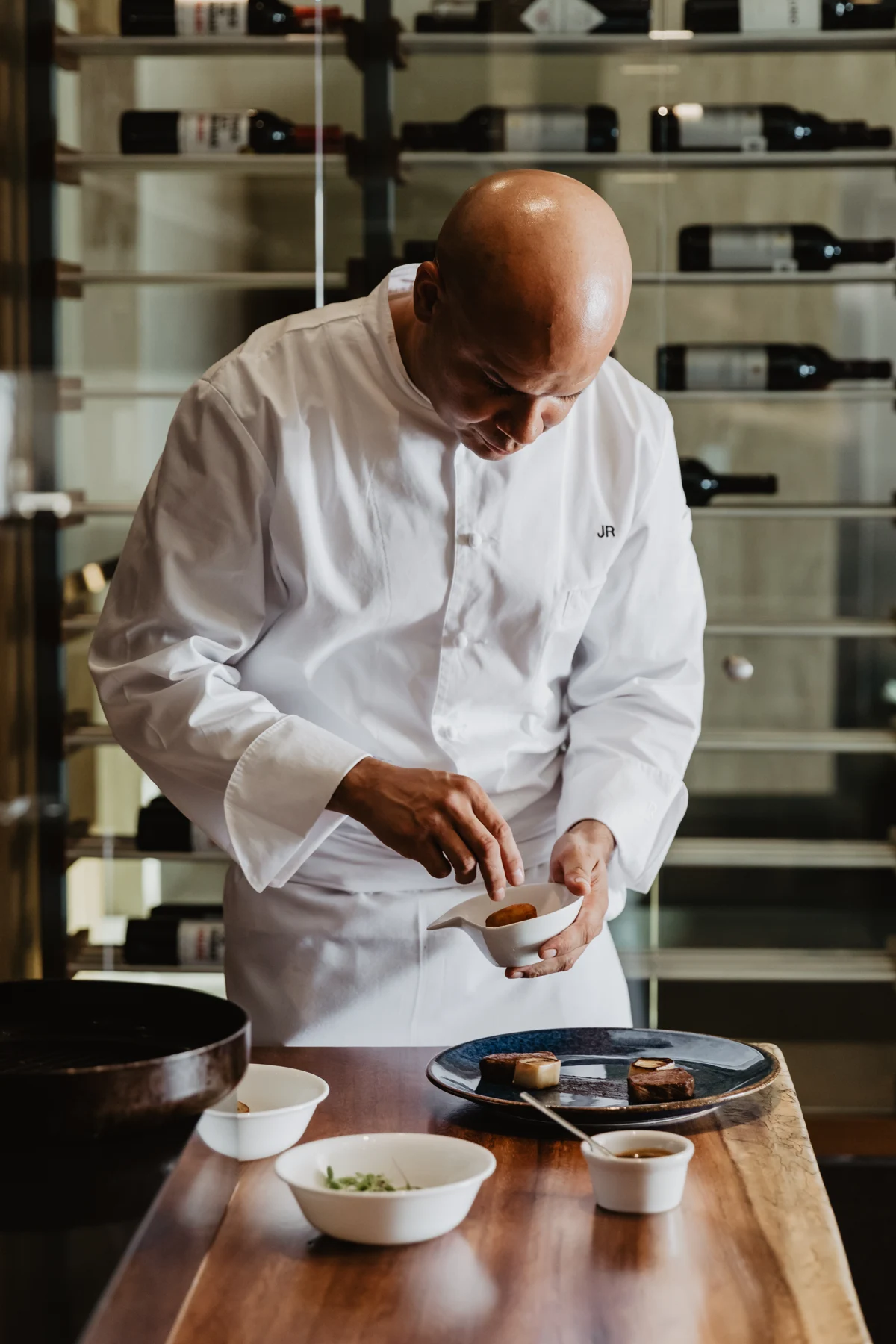 A chef carefully finishing a dish at Maison de Cortés
