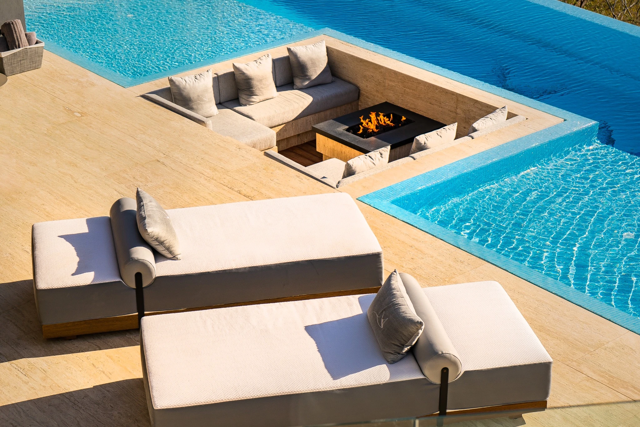 Poolside daybeds and a sunken lounge with a fire feature