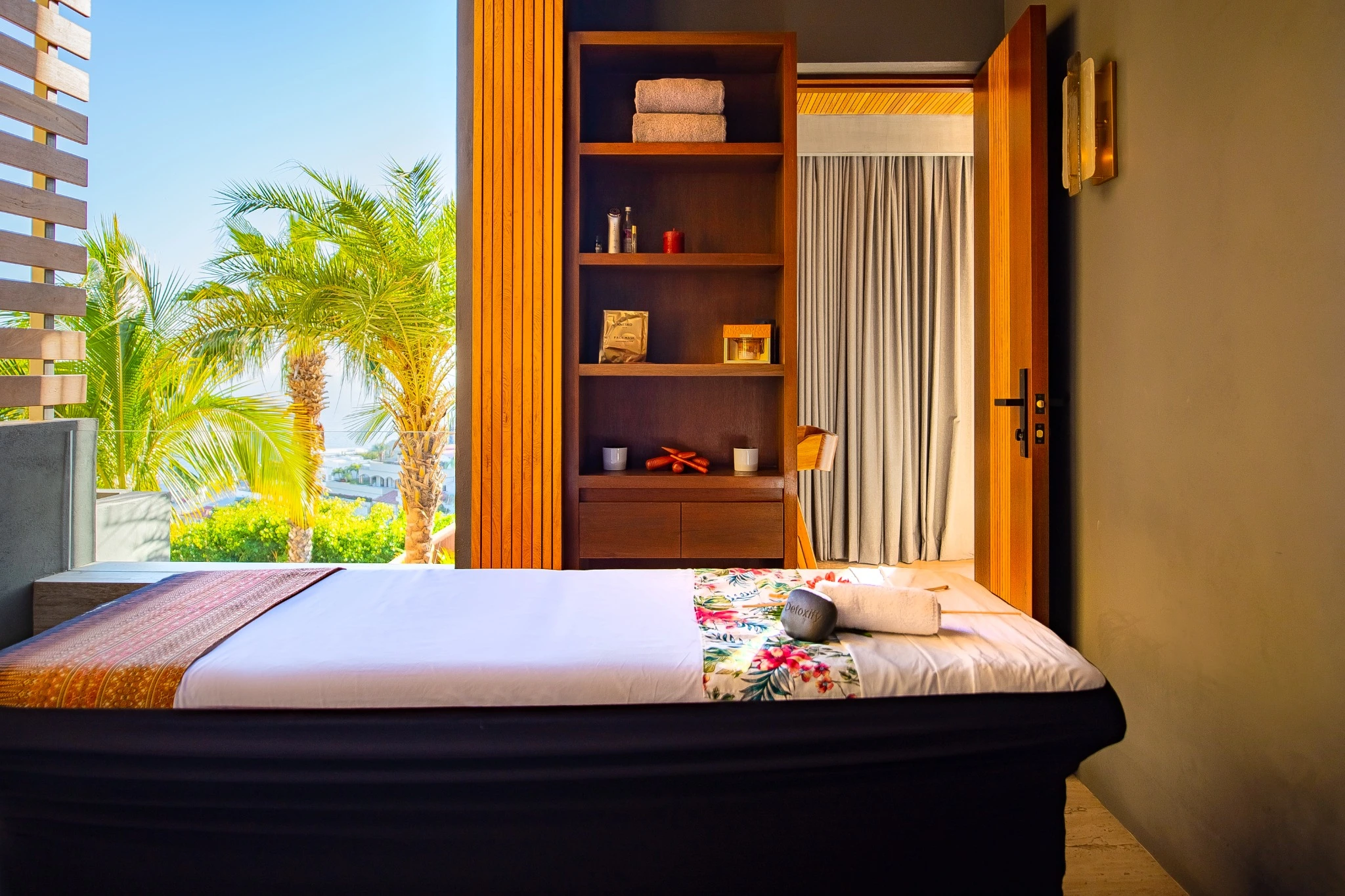 Private villa spa with a massage table and views of sunlit palms